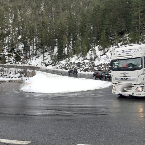 Ein weißer Lkw der Marke DAF fährt auf einer kurvenreichen Straße in einer winterlichen Landschaft.