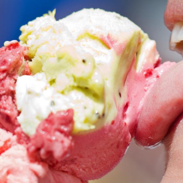 Eine Person isst ein Eis mit Erdbeer-, Kiwi- und Sahnegeschmack.