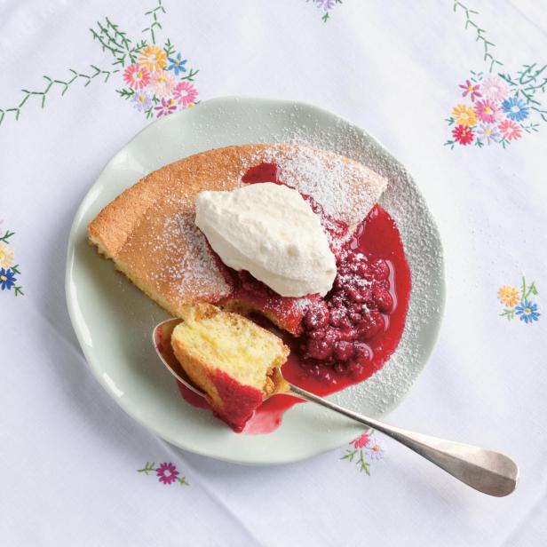 Ein Stück Omelett soufflé mit Himbeersoße und Schlagsahne auf einem Teller.