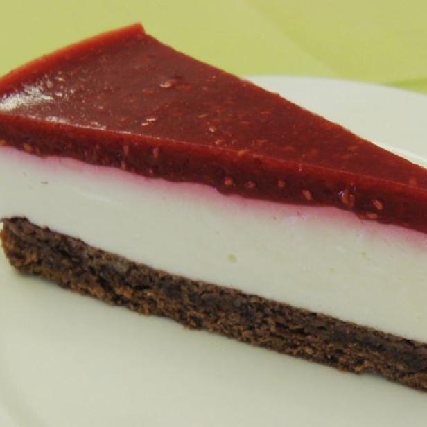 Ein Stück Käsekuchen mit Himbeerguss auf einem Teller.