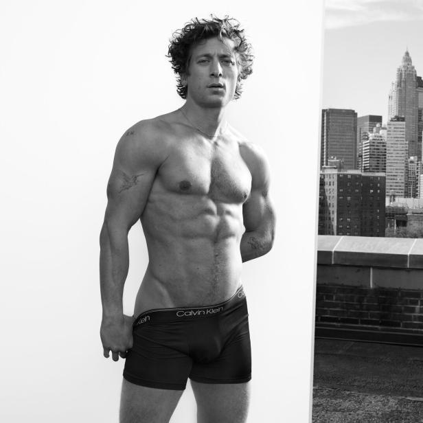 Ein muskulöser Mann posiert in Calvin Klein Unterwäsche vor einer Skyline in Schwarzweiß.