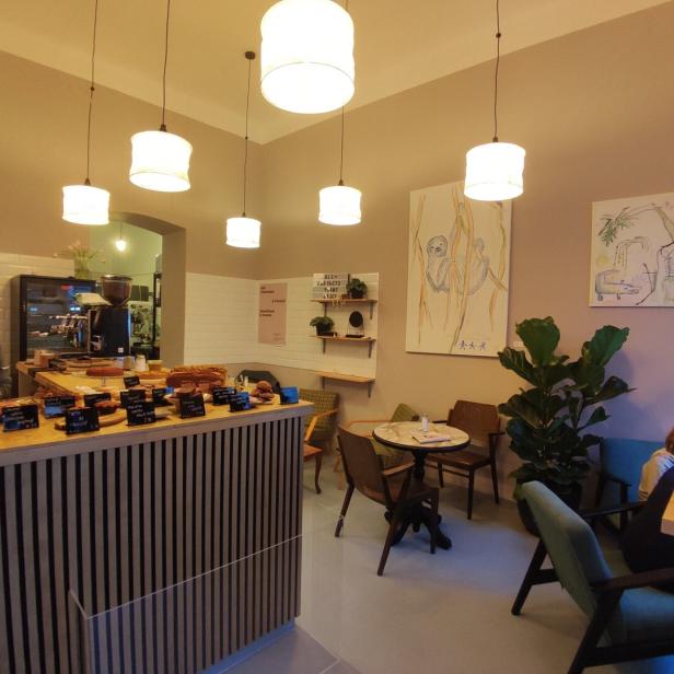 Innenansicht eines Cafés mit einer Theke voller Gebäck und Sitzgelegenheiten.
