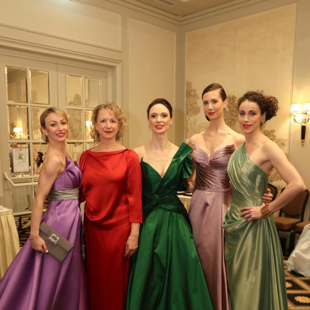 Fünf Frauen posieren in farbenprächtigen Abendkleidern für ein Foto.