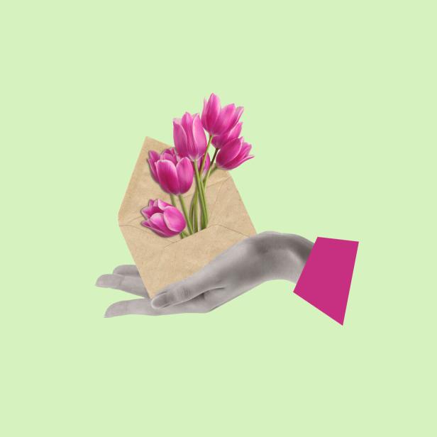 Eine Hand hält einen Briefumschlag, aus dem rosa Tulpen ragen.
