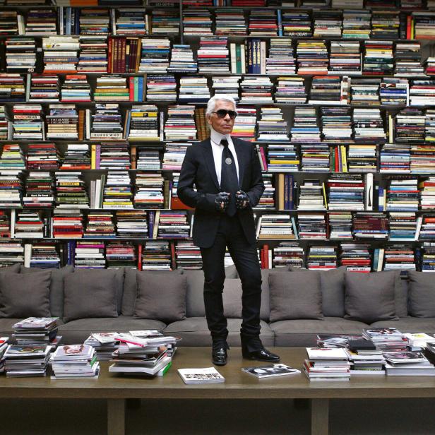 Karl Lagerfeld posiert vor einer Wand voller Bücher.
