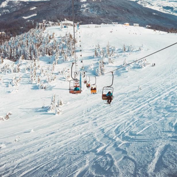 Skifahrer werden mit einem Sessellift auf einen schneebedeckten Berg befördert.