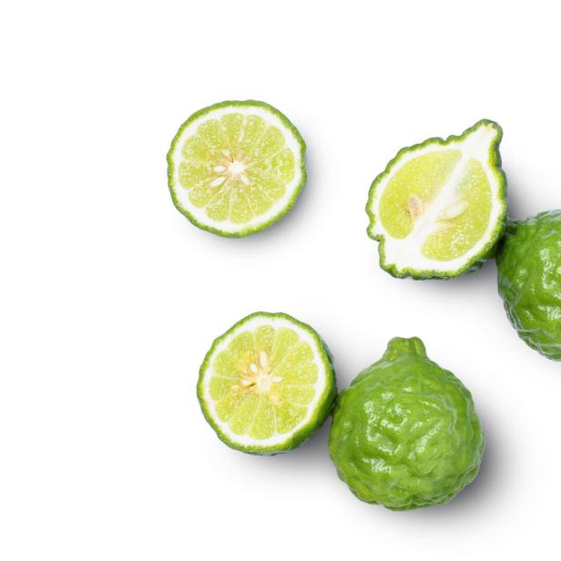 Mehrere grüne Bergamotte-Zitrusfrüchte liegen auf einem weißen Hintergrund.