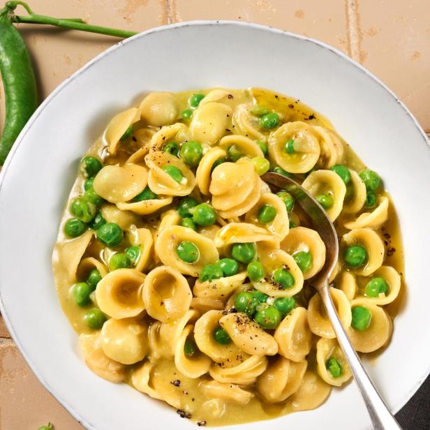 Orecchiette-Nudeln mit Erbsen in einer hellen Sauce werden mit einem Löffel serviert.