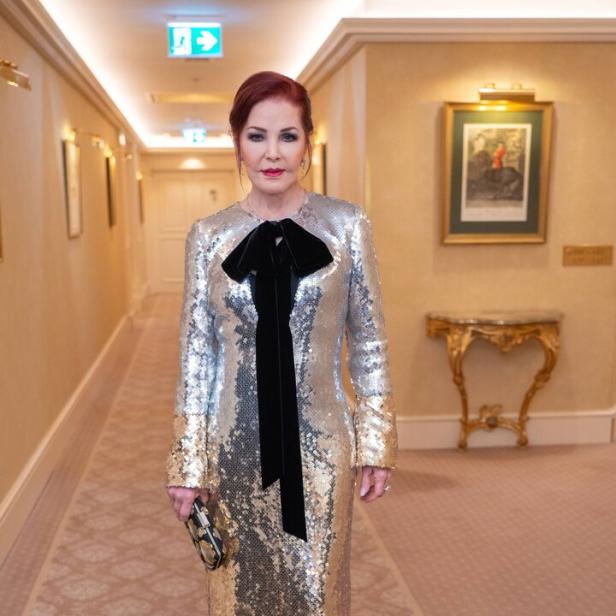 Priscilla Presley in einem silber-goldenen Paillettenkleid mit schwarzer Schleife.