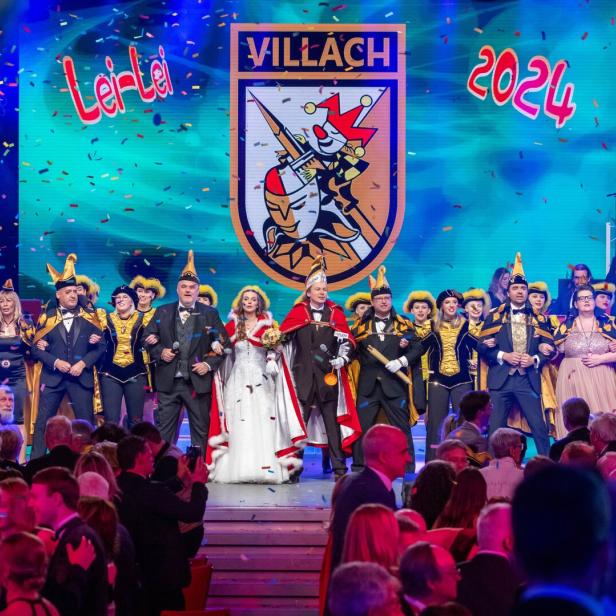 Eine Gruppe von Menschen in Karnevalskostümen steht auf einer Bühne in Villach, 2024.