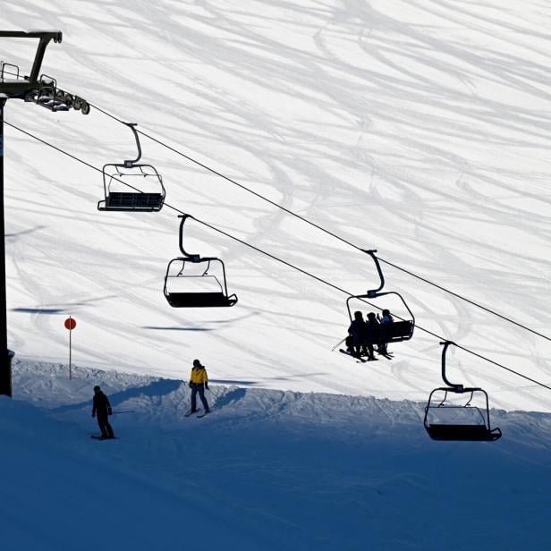 Eine Seilbahn befördert Skifahrer über eine schneebedeckte Piste.