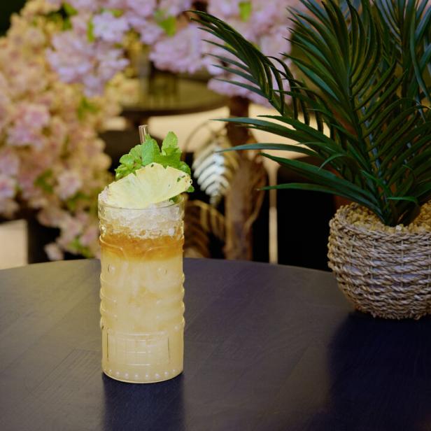 Ein Mai Tai Rum-Cocktail, garniert mit Ananas und Minze, steht auf einem Tisch.