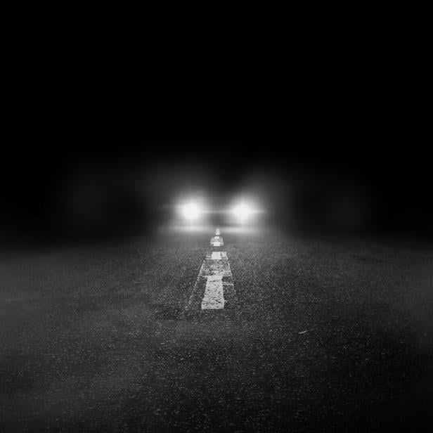 The lonely road at night with the car running.