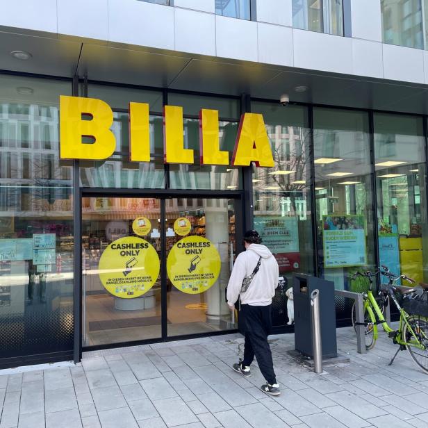 Ein Mann betritt einen Billa-Supermarkt, an dem Fahrräder geparkt sind.