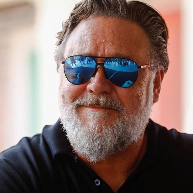 Russell Crowe mit Sonnenbrille und grauem Bart blickt zur Seite.