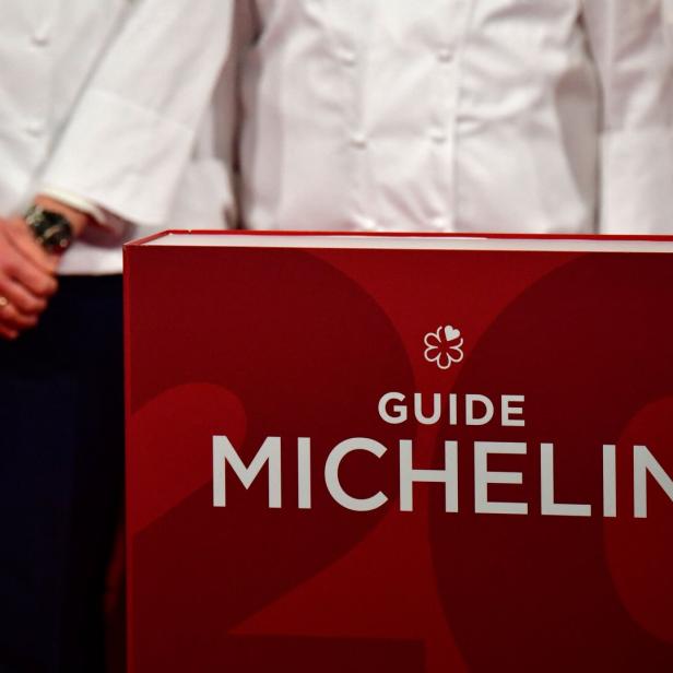 Köche stehen hinter einem großen „Guide Michelin“-Buch.