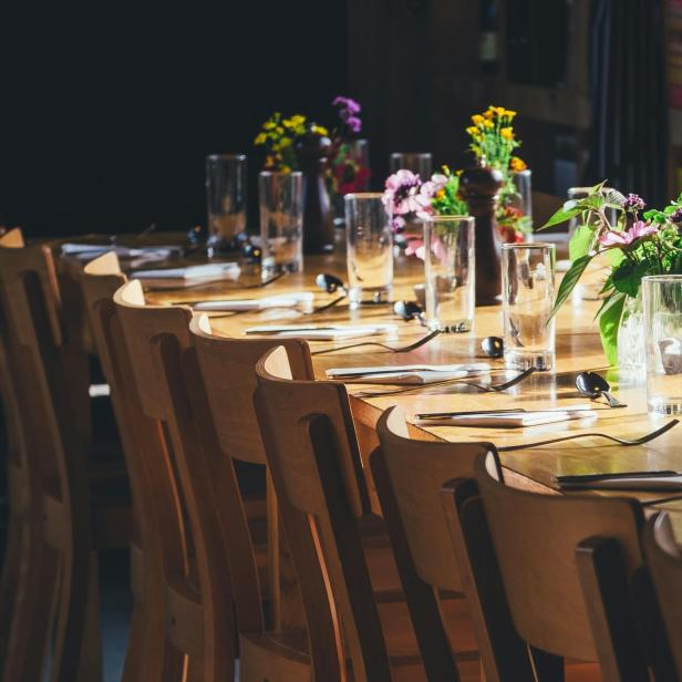 Ein gedeckter Holztisch mit Blumenvasen und Gläsern in einem Restaurant.