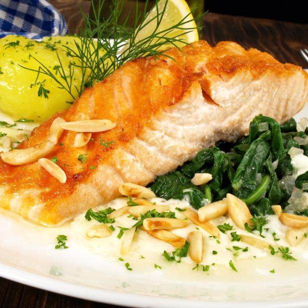 Ein Teller mit gebratenem Lachs, Spinat und einer Kartoffel mit Dill.