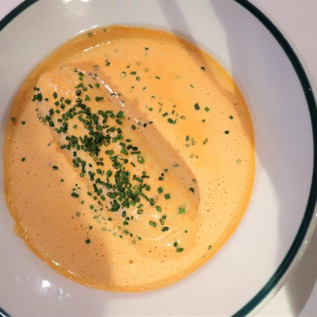 Ein Teller mit Fisch in Sauce, garniert mit Schnittlauch.