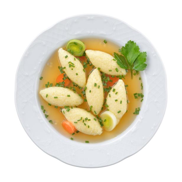 Eine Suppe mit Grießklößchen, Lauch, Karotten und Schnittlauch in einem weißen Teller.