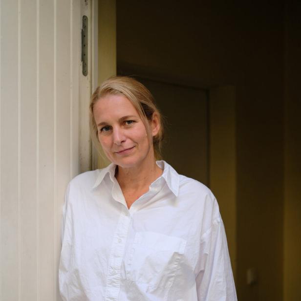 Eine Frau mit blonden Haaren lehnt an einer Tür.