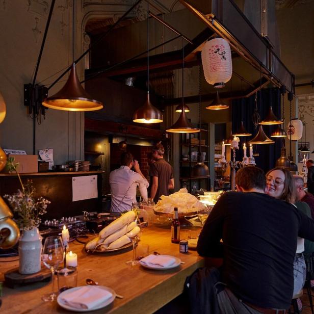 In einem Restaurant sitzen Gäste an der Bar und genießen die Atmosphäre.