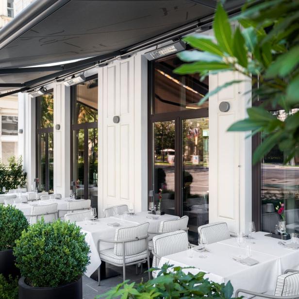 Einladende Terrasse eines Restaurants mit gedeckten Tischen und grünen Pflanzen.