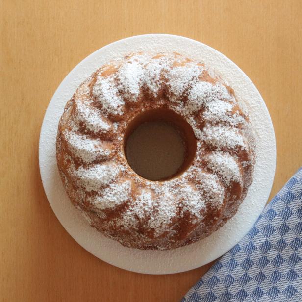 Ein Gugelhupf auf einem Teller, mit Puderzucker bestäubt.