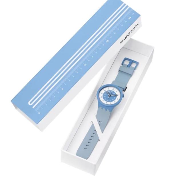 Eine hellblaue Swatch-Uhr liegt in einer weißen Schachtel, deren Deckel daneben liegt.