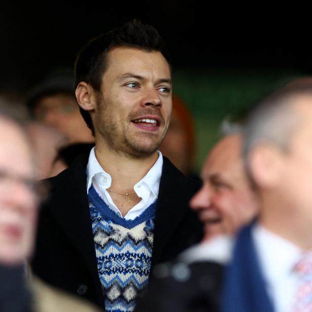 Harry Styles schaut bei einer Veranstaltung auf der Tribüne zu.
