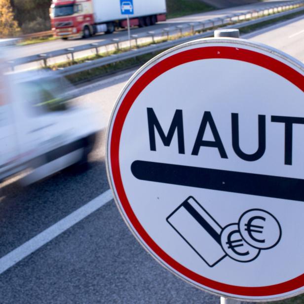 Ein rundes Verkehrsschild mit der Aufschrift „MAUT“ und Symbolen für Bezahlung steht an einer Autobahn.