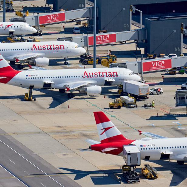 Mehrere Flugzeuge der Austrian Airlines stehen auf dem Rollfeld eines Flughafens.