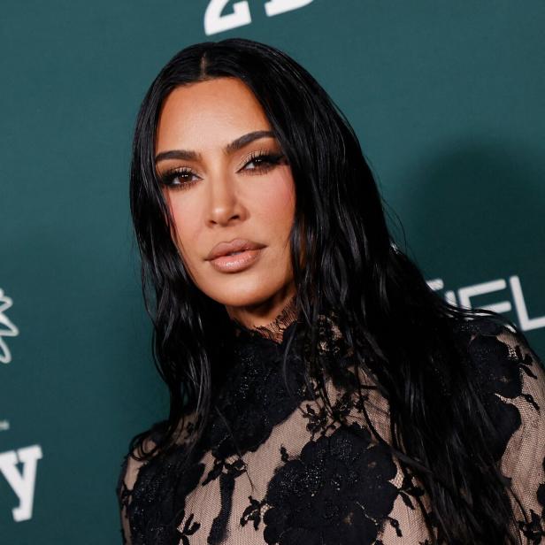 Kim Kardashian posiert auf einem Event mit einem schwarzen Spitzenkleid.