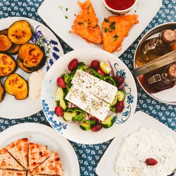 Eine Auswahl griechischer Vorspeisen, darunter Salat, Auberginen und Brot.