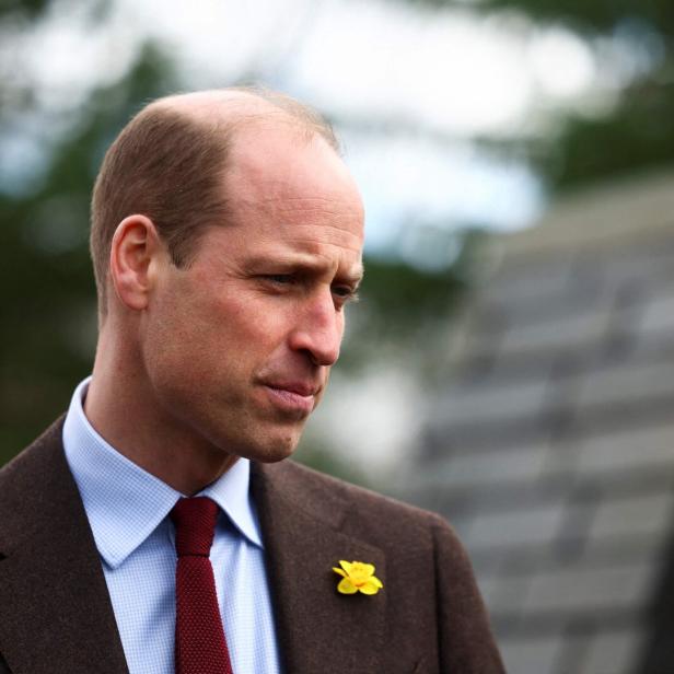 Prinz William trägt einen braunen Anzug mit einer gelben Narzisse am Revers.