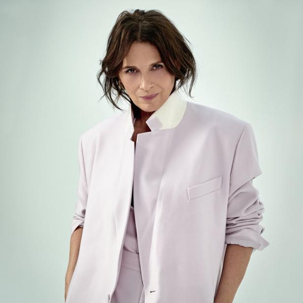 Porträt von Juliette Binoche in einem helllila Hosenanzug.