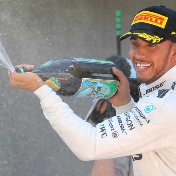 Lewis Hamilton feiert mit einer Champagnerdusche.