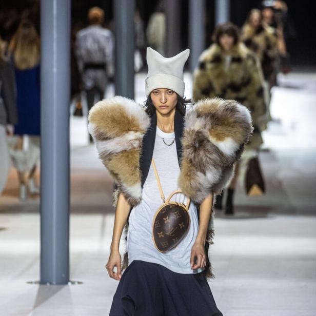 Ein Model posiert für Louis Vuitton in einem Pelzkragen und einer eiförmigen Handtasche.