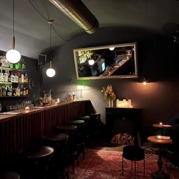 Innenansicht einer Bar mit dunkler Einrichtung und rotem Teppich.