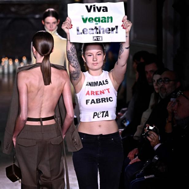 Eine Frau hält ein Plakat mit der Aufschrift „Viva Vegan Leather“ hoch.