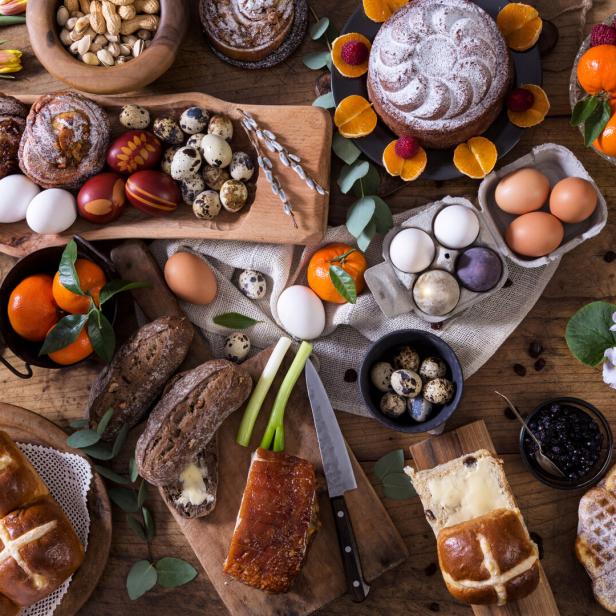 Ein Ostertisch reich gedeckt mit Eiern, Kuchen, Brot, Waffeln und Obst.