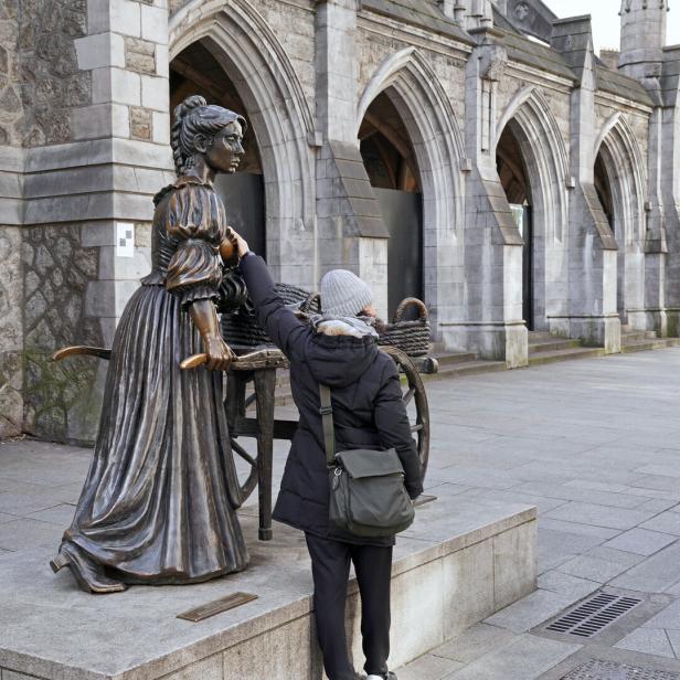 Eine Touristin berührt die Brust der Molly-Malone-Statue.