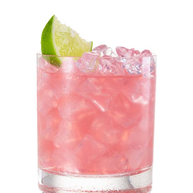 Ein rosa Cocktail mit Eiswürfeln und einer Limettenscheibe in einem Glas.