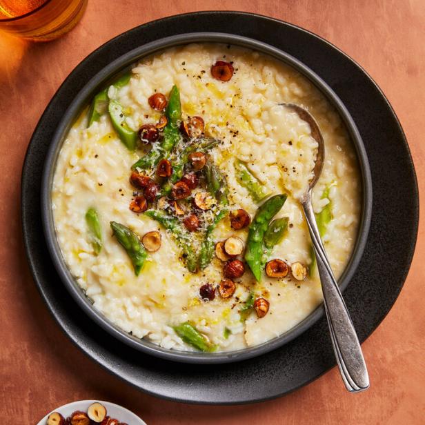 Ein Teller Risotto mit Spargel und Haselnüssen, garniert mit Parmesan und Pfeffer.