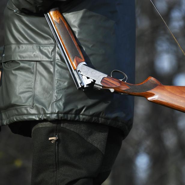 Ein Mann trägt ein offenes Jagdgewehr über der Schulter.