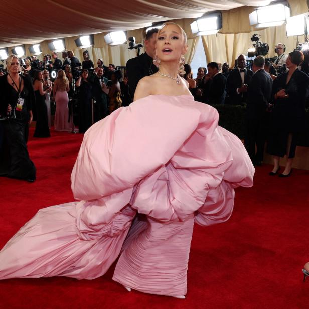 Ariana Grande in einem auffälligen, rosa Kleid auf einem roten Teppich.