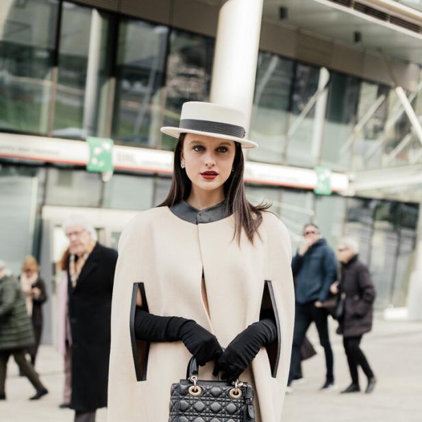 Ein Model mit Hut und Cape auf der Fashion Week.