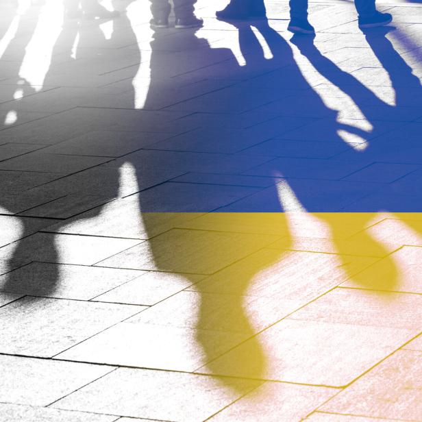 Schatten von Menschen auf einem Bürgersteig, überlagert von den Farben der ukrainischen Flagge.