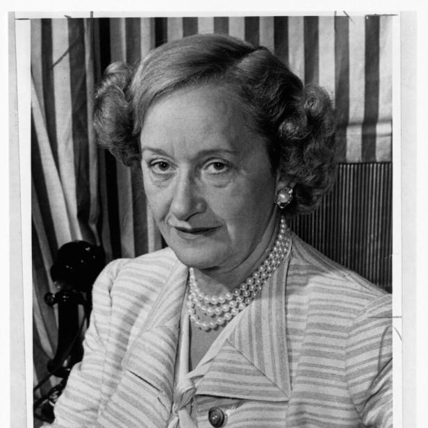 Hattie Carnegie trägt eine Perlenkette und einen gestreiften Blazer.