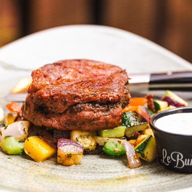 Ein „Le Burger“-Gericht mit Gemüse und einem Dip wird serviert.